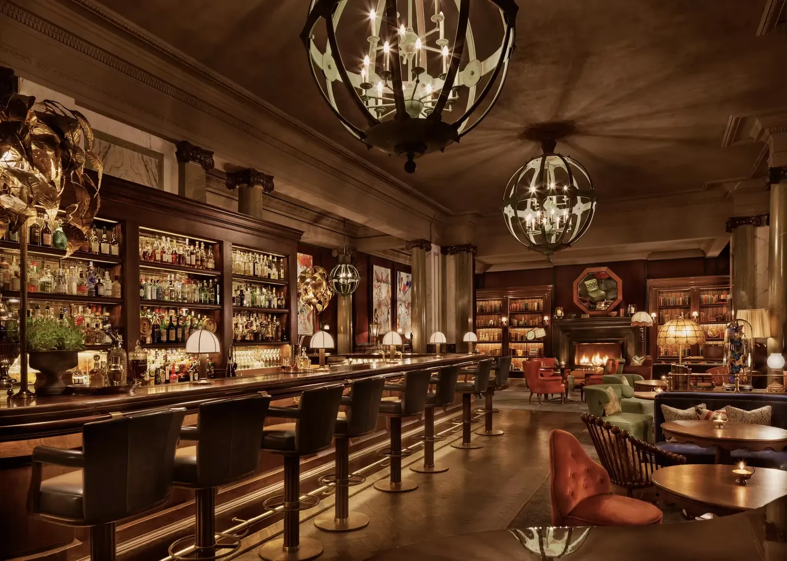 The long polished bar, library shelves and glowing chandeliers at Scarfes Bar